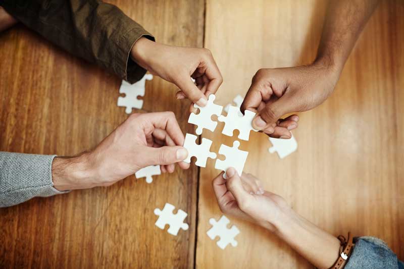 Fyra personer som håller ihop fyra matchande pusselbitar