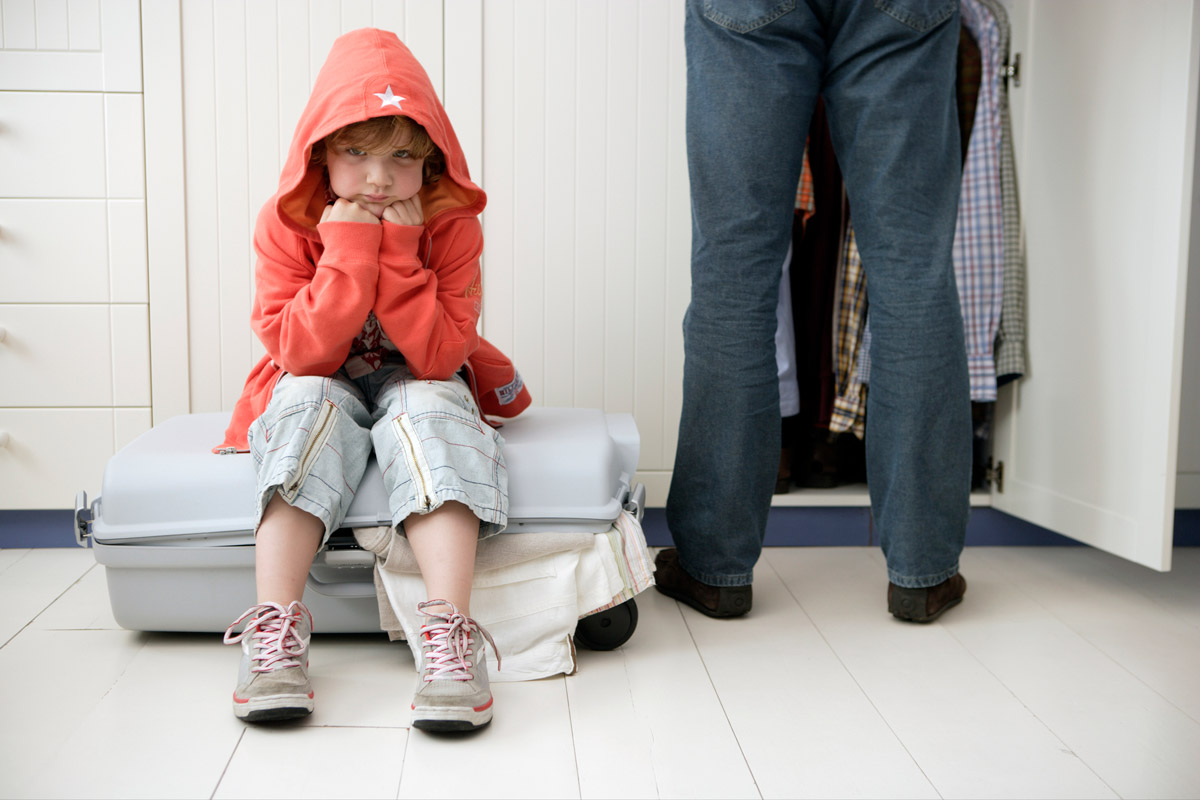 Bild på ett surt barn som sitter på en resväska